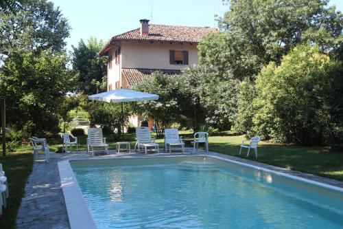 a swimming pool with chairs and an umbrella and a house at Locanda Del Molino Vecchio in Magliano Alfieri