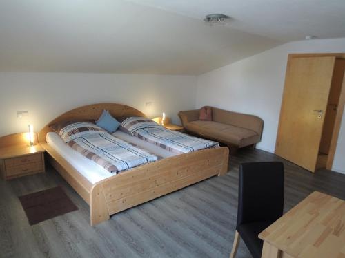 a bedroom with a large wooden bed and a couch at Ferienwohnungen Hackl Ulrike in Mauth