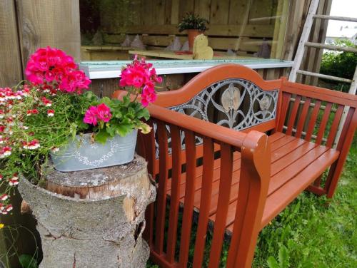 a wooden bench sitting on a tree stump with flowers at Ferienwohnungen Hackl Ulrike in Mauth
