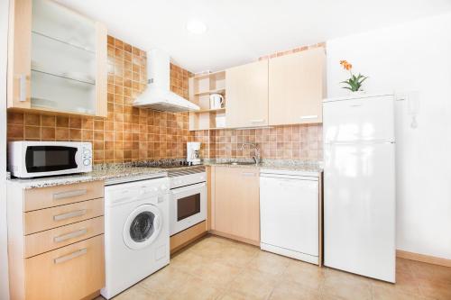a kitchen with white cabinets and a washer and dryer at Apartaments Les Terrasses del Tarter in El Tarter
