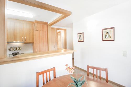 a kitchen with wooden cabinets and a table and chairs at Apartaments Les Terrasses del Tarter in El Tarter