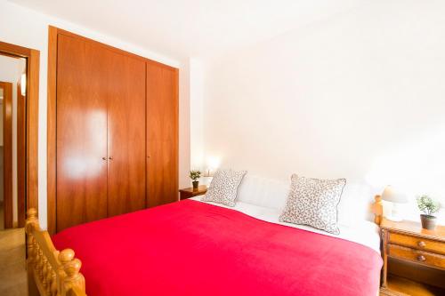 a bedroom with a red bed with a wooden cabinet at Apartaments Les Terrasses del Tarter in El Tarter
