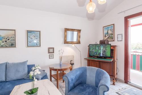 a living room with a blue couch and a tv at Ferienwohnungen Velijoze in Poreč