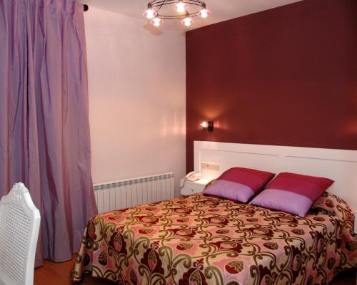 a bedroom with a bed with red and purple pillows at Hotel HC Sigüenza in Sigüenza