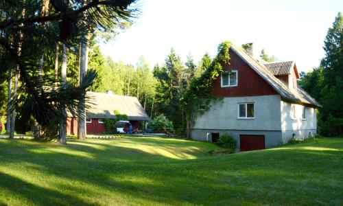 a red and white house in a yard with trees at Roosi Holiday Home in Rannaküla