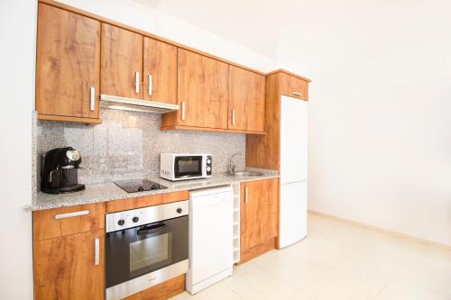 a kitchen with wooden cabinets and a microwave at Apartaments Les Terrasses del Tarter in El Tarter