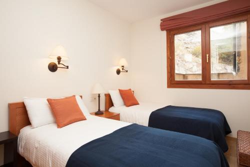 two beds in a room with a window at Apartaments Les Terrasses del Tarter in El Tarter