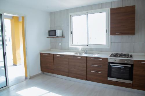 a kitchen with wooden cabinets and a sink and a window at Le Ndiambour Hôtel et Résidence in Dakar