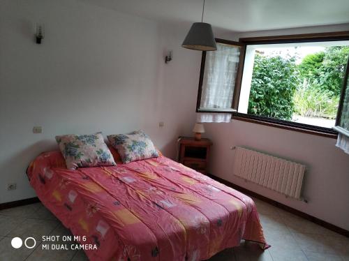 a bedroom with a bed with a red comforter and a window at Les Bananiers in Capbreton