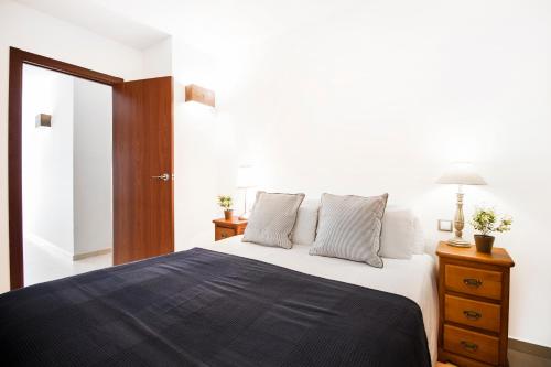 a bedroom with a bed with a black blanket and pillows at Apartaments Les Terrasses del Tarter in El Tarter