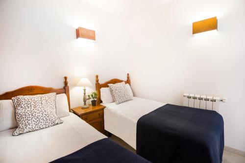 a bedroom with two beds and a night stand with two lamps at Apartaments Les Terrasses del Tarter in El Tarter