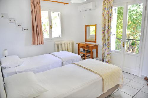 two beds in a room with a mirror and windows at Korakias Skorpidi in Yénion