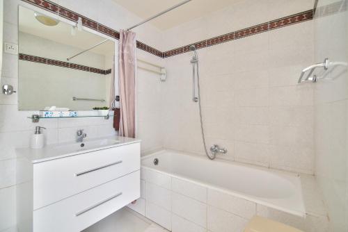 une salle de bain blanche avec une baignoire et un lavabo dans l'établissement Cannes Film Festival Beach Apartment, à Cannes