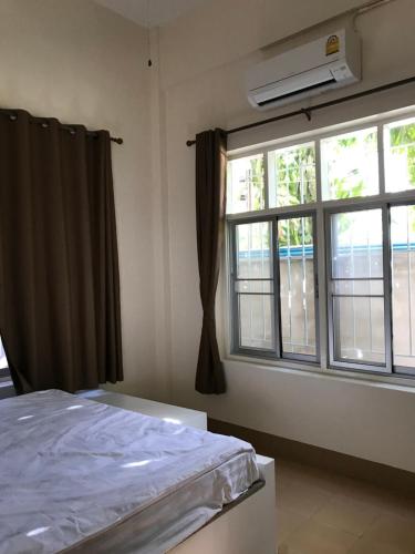 een slaapkamer met een bed en een raam bij Tk Home 1 in Lampang