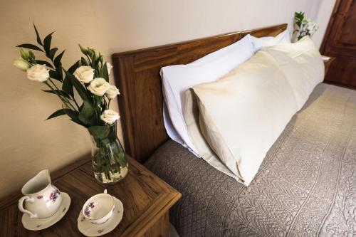 a vase of flowers on a table next to a bed at PienzaLettings "Casa Olivieri" in Pienza