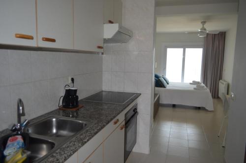 una pequeña cocina con fregadero y un dormitorio en Apartaments Gibert, en Sant Antoni de Calonge