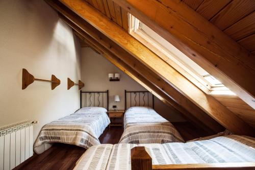 three beds in a room with an attic at Hostal La Plaça in Erill la Vall