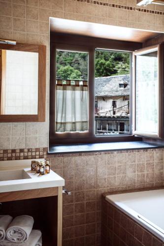 a bathroom with a tub and a sink and a window at Hostal La Plaça in Erill la Vall