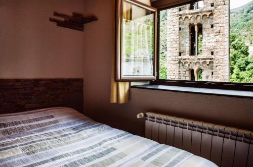 a bedroom with a bed and a window at Hostal La Plaça in Erill la Vall