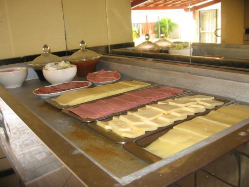 un mostrador con diferentes tipos de queso y carne en Laina´s Place Hotel, en Natal