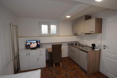 a kitchen with white cabinets and a tv on the wall at Apartment Terrotstraße in Stuttgart