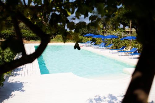una piscina con tumbonas y sombrillas azules en B&B Il Cavaliere Tropea, en Santa Domenica