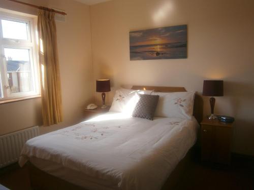 1 dormitorio con 1 cama blanca con 2 lámparas y una ventana en Quay West Ireland, en Westport