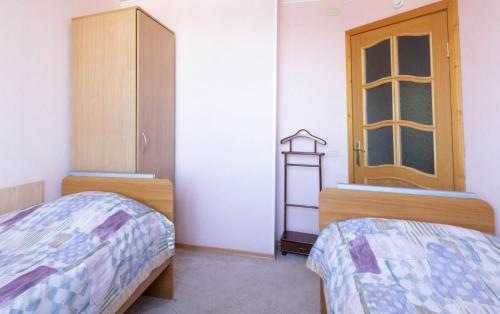 a bedroom with two beds and a cabinet and a window at Leningrad Hotel in Cherepovets