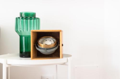 a clock in a wooden box next to a green vase at Feel Nazaré - Boutique Apartments in Nazaré