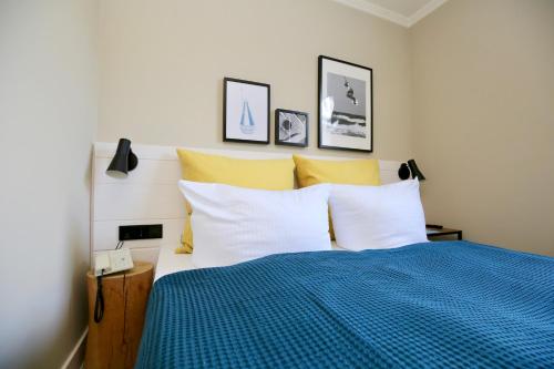 a bedroom with a bed with blue and yellow pillows at Hotel Boje06 in Heringsdorf