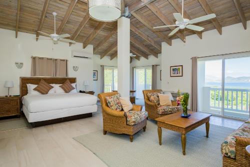 a bedroom with a bed and chairs and a couch at Mount Nevis Hotel in Nevis