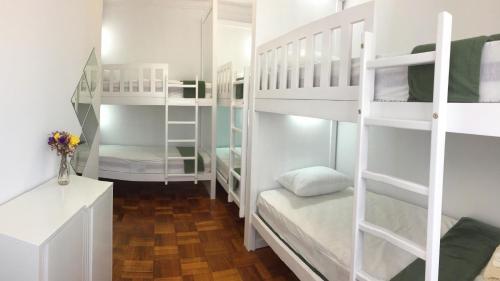 a room with white bunk beds and a desk at Hostel das Flores in Senhora da Hora