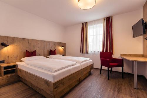 a bedroom with a large bed and a red chair at Brauerei Gaststätte Stierberg in Obertaufkirchen