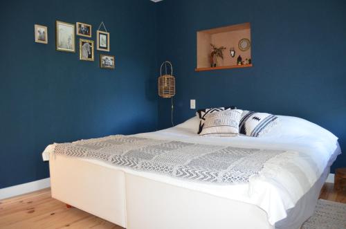 ein Schlafzimmer mit einem weißen Bett und einer blauen Wand in der Unterkunft Mas Mialou in Saint-Jean-du-Gard