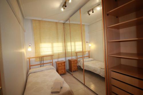 a small bedroom with two beds and a mirror at Piso Vacacional en Murcia in Beniaján