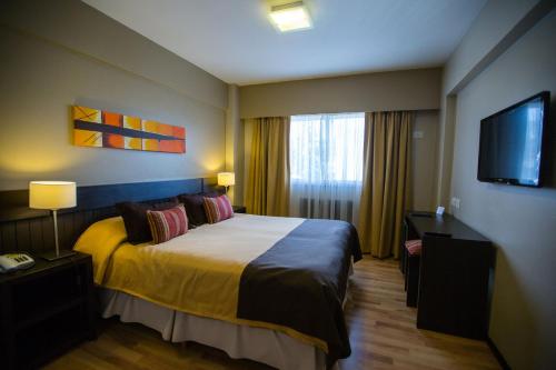 a hotel room with a bed and a flat screen tv at Carlos V Patagonia in San Carlos de Bariloche