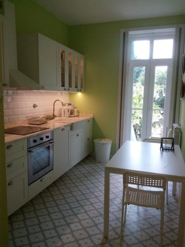 a kitchen with white cabinets and a table and a window at Casa Familiar do Porto in Porto