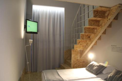 a bedroom with a bed with a television and a staircase at StayInn City - Póvoa de Varzim in Póvoa de Varzim