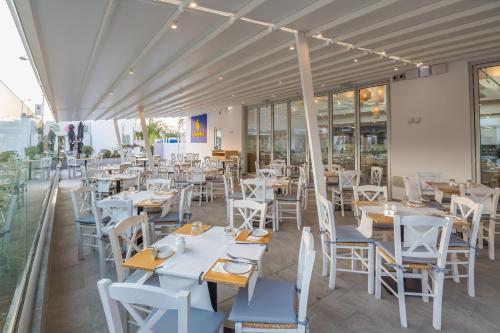 an empty restaurant with white tables and chairs at Protaras Plaza Hotel in Protaras