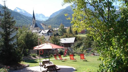 a group of chairs and an umbrella in a yard at Hotel Crusch Alba Sta Maria in Sta Maria Val Müstair