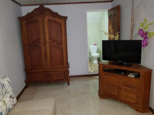a living room with a flat screen tv on a wooden cabinet at Orchid Sunset Guest House in Baie Lazare Mahé