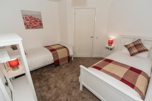 a bedroom with two beds and two red lamps at Silver Key Apartments in Inverness