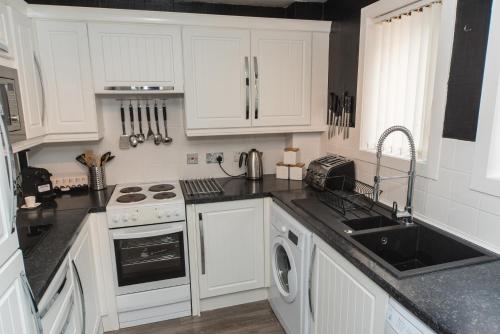a kitchen with white cabinets and a sink at Silver Key Apartments in Inverness