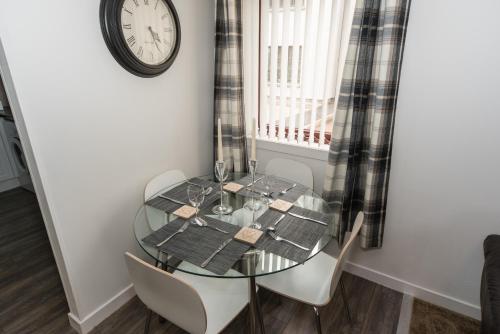 a dining room table with chairs and a clock on the wall at Silver Key Apartments in Inverness