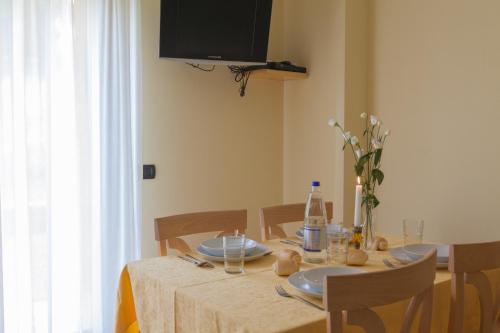 a dining room table with plates and a television on the wall at Residence Hotel Raggio Di Luce in Ponte di Legno