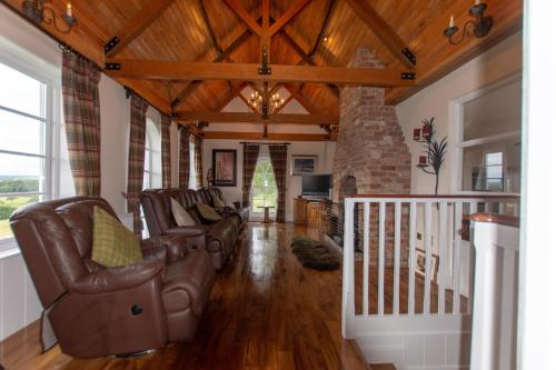 a living room with leather chairs and a fireplace at Pellipar Gatelodge in Bovevagh