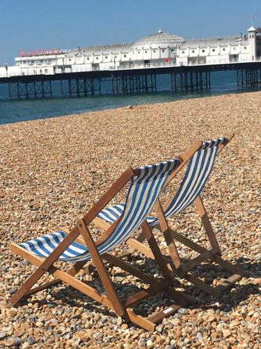 a chair sitting on a beach with a pier at Kemp Town Sea View Balcony Apartment in Brighton & Hove