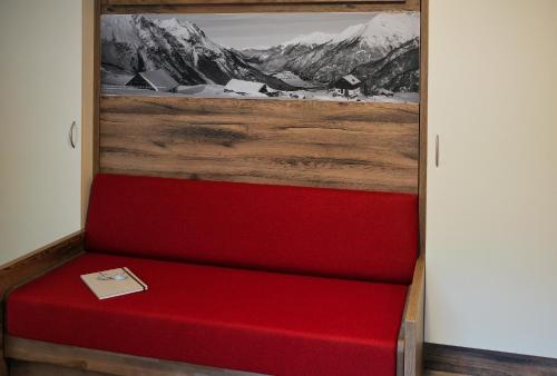 a red bench in a room with a picture of mountains at Apart Felsenhof in Längenfeld