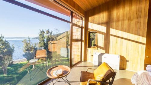 a room with a balcony with a view of the ocean at Casas Martín Pescador, Lago Huillinco, Chiloe in Chonchi