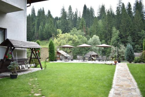 a lawn with tables and umbrellas in a yard at Clematis House in Voronet